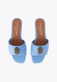 Sandali blu in pelle con upper trapuntato, caratterizzati da un elemento decorativo in oro su una tracolla ampia. Suola piatta, design open-toe.