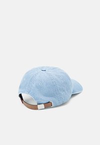 Világoskék denim baseball sapka íveltлегенylobarbour-hatgeira, állítható barna szíjjal a hátulján, és hat szellőzőnyílással a tetején.
