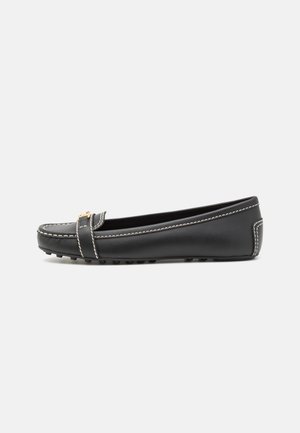 Black leather loafer with white stitching, rounded toe, and a decorative strap featuring a gold-toned accent; rubber sole with grip.