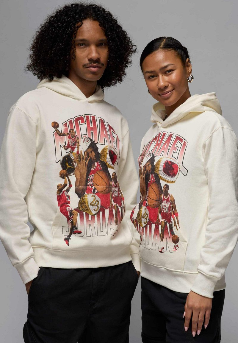 Kermansävyisissä huppareissa on värikäs Michael Jordan -kuva koripalloteemoilla, teksturoitua kangasta ja kengurupussit, joita käyttävät kaksi mallia.