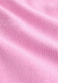 Svetlo rožnata bombažna tkanina z gladko teksturo in subtilnim rebrastim vzorcem, ki prikazuje mehke gube in zavoje.