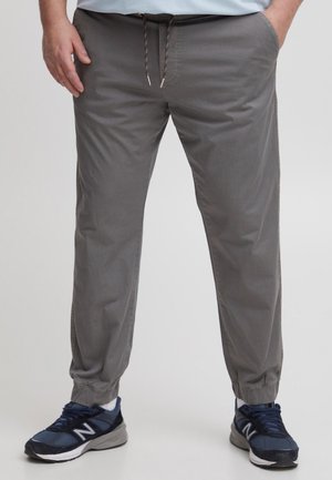 Pantalons de jogging gris clair avec une taille élastique et un cordon de serrage réglable, dotés de poches latérales et de poignets élastiques aux chevilles.
