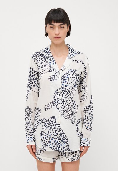 Camisa de pijama de manga larga en blanco con estampado de leopardo en marino, con cuello notch, cierre de botones en el frente y pantalones cortos a juego. Tela suave y ligera.
