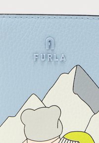 Πορτοφόλι από δέρμα σε ανοιχτό μπλε με ανάγλυφο λογότυπο "FURLA", εικονογραφημένα βουνά σε λευκό και γκρι, και παιχνιδιάρικο σχέδιο χαρακτήρα.