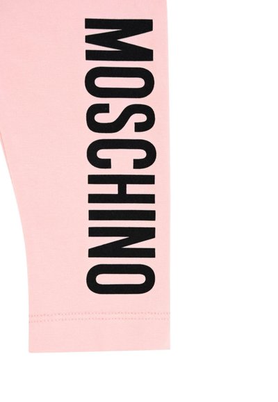 Różowe legginsy wykonane z bawełny, o dopasowanym kroju, z wyraźnym czarnym napisem "MOSCHINO" umieszczonym pionowo z boku. Gładka tekstura i prosty dół.