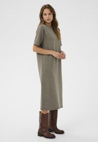 Pelēks, līdz Ceļiem garš T-kreklu kleita ar īsām piedurknēm. Mīksta adīta auduma, brīvs piegriezums. Saskaņota ar brūnām ādas līdz ceļiem garām zābakiem.