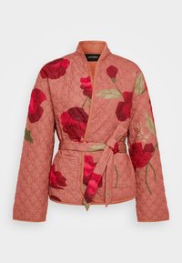 Polstret omslagjakke i støvet rosa med quiltet tekstur, prydet med store røde blomster mønstre, lange ærmer og et bånd i taljen.