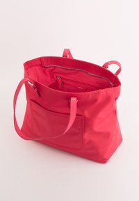 Bolso tote rosa hecho de nailon, con dos asas para el hombro, un bolsillo interior con cremallera y un bolsillo exterior tipo deslizante. Textura suave.
