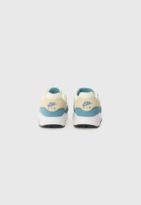 Nike Air Sneakers mit einem cremefarbenen Obermaterial und blauen Akzenten, einem gepolsterten Kragen und einer weißen Zwischensohle. Texturiertes Gummiaußensohle.