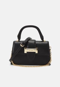 Svart läderhandväska med guld fyrkantigt lås, handtag upptill, justerbar axelrem och guldkedjeaccent mot en vit bakgrund.