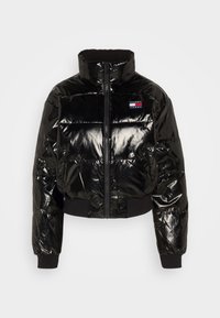 Giacca a vento nera con finitura lucida, design corto, collo alto, zip frontale e polsini a costine. Presenta un piccolo logo sul petto.