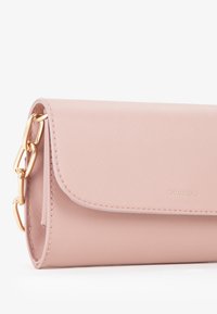 Portafoglio in pelle sintetica rosa con una texture liscia, caratterizzato da un accento in catena dorata e una chiusura a patta. Il nome del marchio "MIRIADGE" è impresso.