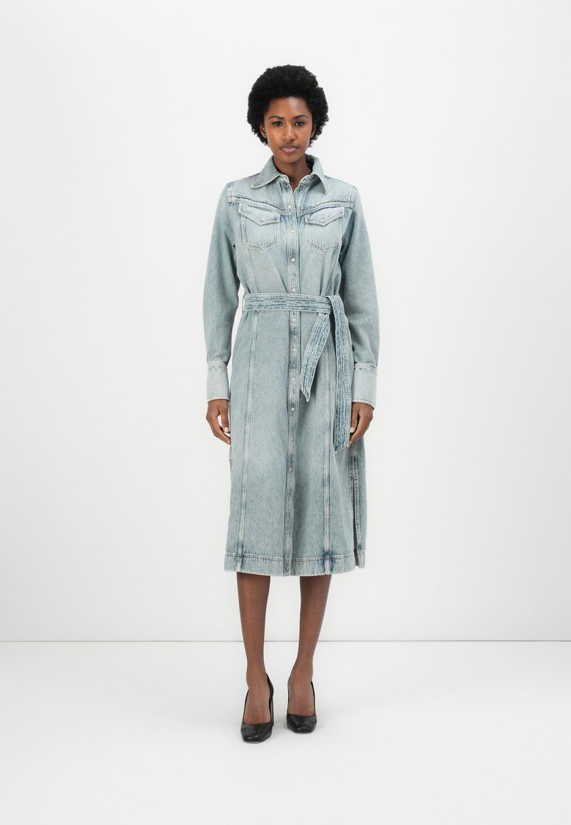Light blue denim shirt dress with long sleeves, button-down front, chest pockets, waist tie, and ankle-length hem. Smooth texture and classic design.