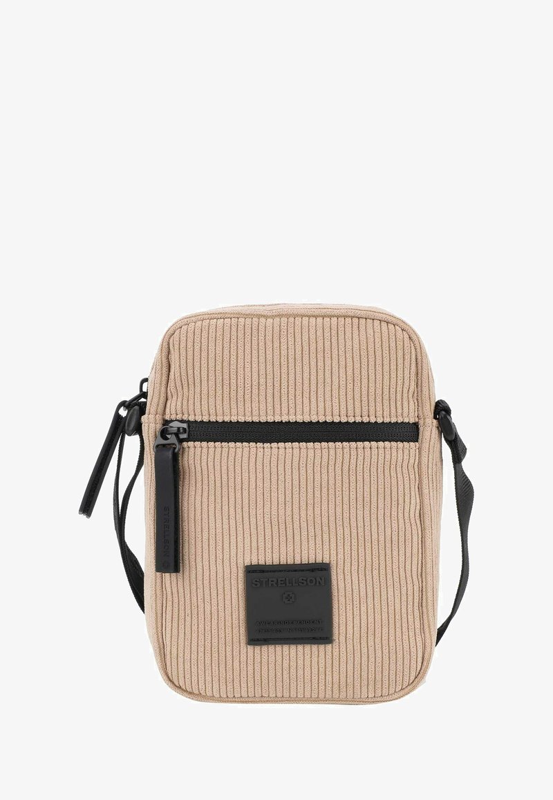 Borsa a tracolla in tessuto a coste beige con una tasca zip nera, patch in pelle con logo e tracolla regolabile. Superficie testurizzata con righe orizzontali.