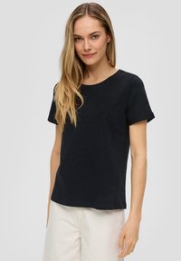 Schwarzes kurzärmliges T-Shirt mit klassischem Rundhalsausschnitt, das einen entspannten Schnitt und einen weichen, strukturierten Stoff bietet.