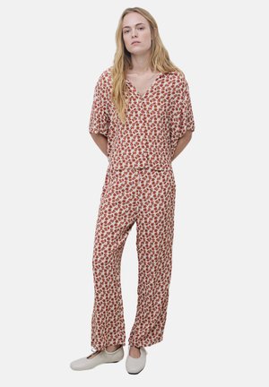 Jumpsuit floral con patrones rojos y blancos, mangas cortas, escote en V y pantalones holgados. Fabricado con tela ligera.