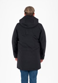 Giacca nera impermeabile con cappuccio, caratterizzata da un design elegante, un taglio di lunghezza media e una texture liscia. Appare funzionale con dettagli minimali.