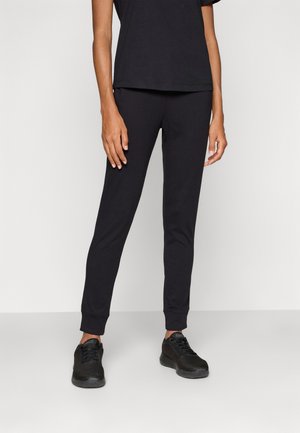 Svart bomullsjogging med ribbestrikkede mansjetter og slim fit, kombinert med svarte mesh-sneakers og en enkel svart t-skjorte.
