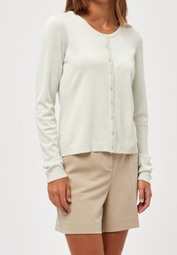 Ljusgrön stickad cardigan med rund halsringning, långa ärmar och knäppning, med ribbade detaljer längs kanterna.