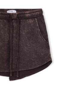 Shorts marron à taille élastique avec cordon de serrage, poches avant, et un tissu doux et texturé présentant un motif de délavage subtil.
