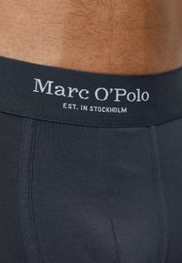 Boxer aderenti grigio scuro con una morbida vita elasticizzata che mostra la scritta "Marc O'Polo EST. IN STOCKHOLM" in bianco. Tessuto liscio e aderente.