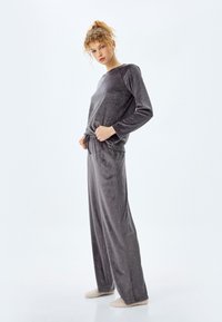 Graues Samt-Pyjama-Set mit langärmligem Oberteil und Pants mit Zugband, verziert mit kleinen silbernen Punkten für ein dezentes Detail.