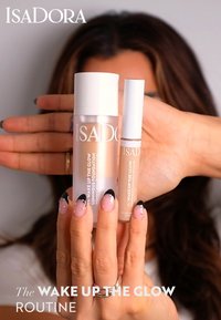 IsaDora beauty products featuring a luminous foundation in a frosted bottle and a concealer in a sleek tube, both with light beige labels.