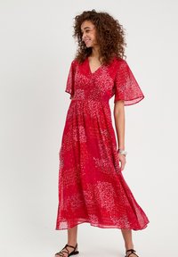 Abito midi rosso con motivo floreale, maniche a farfalla corte e scollatura a V. Il tessuto leggero cade morbido con una vita elasticizzata.