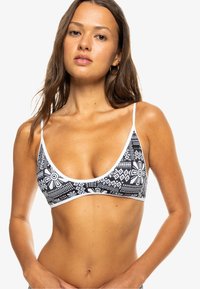Top de bikini con patrón en blanco y negro, diseño triangular, tirantes finos y ribete en blanco contrastante. Presenta motivos geométricos y florales.