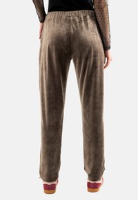 Pantalones de tela marrón y suave con un corte relajado, que cuentan con una cinturilla elástica y una textura lisa. El usuario los combinó con zapatos coloridos.