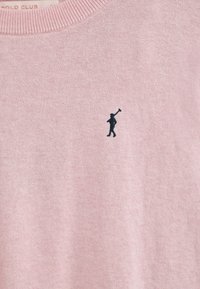 Maglione rosa chiaro realizzato in tessuto morbido, con una piccola figura nera ricamata che tiene un bastone sul lato sinistro del petto. Collo a costine.