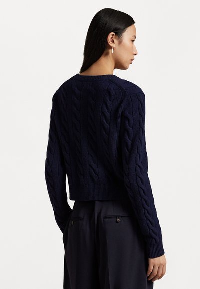 Laivastonsininen, verkkokudottu neulepaita, jossa on lyhyt malli, kontrastivärinen resori helmassa ja hihoissa, teksturoitu kuvio sekä leveä pyöreä kaula-aukko.