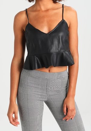 Černý faux kožený crop top s V-výstřihem a tenkými ramínky, s volánkovým lemem. V kombinaci se šedými kostkovanými upnutými kalhotami.