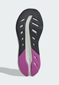Suola di scarpa sportiva nera e viola, con gomma testurizzata e accenti bianchi e scanalature per trazione. Il design è elegante e moderno.