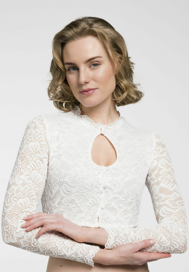 Weiße Spitzenbluse mit einem Schlüsselloch-Ausschnitt, langen Ärmeln und einer Knopfleiste. Zarte florale Muster und strukturierten Stoff sind auffällig.