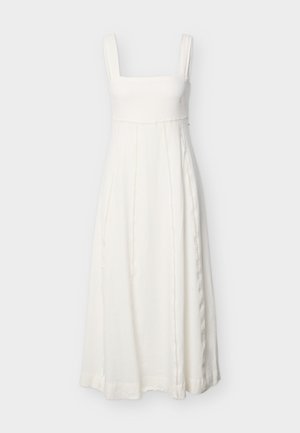 Λευκό αμάνικο μακρύ φόρεμα με τετράγωνο ντεκολτέ και κάθετες διακοσμητικές ραφές, κρεμασμένο σε απλό ανοιχτό φόντο.