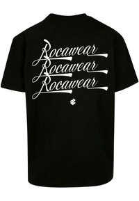 Juodas medvilnės marškinėlis su dideliu baltu kursyvu užrašytu "Rocawear", pakartotu vertikaliai ant nugaros. Klasikinio apvalaus kaklo dizainas, trumpomis rankovėmis.