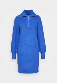 Robe en tricot bleu avec un col haut, demi-fermeture éclair et manches bouffantes longues. Tissu texturé, design ajusté, et l'ourlet tombe au-dessus du genou.