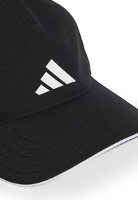 Mustvalge müts, mis on valmistatud struktuursest kangast, millel on külgedel valge kolmerealine logo ja kontrastne valge äärvisääre ääres.