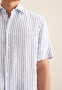 Camicia a maniche corte in blu chiaro e bianco con righe verticali, realizzata in tessuto testurizzato con chiusura con bottoni e dettagli sul colletto.