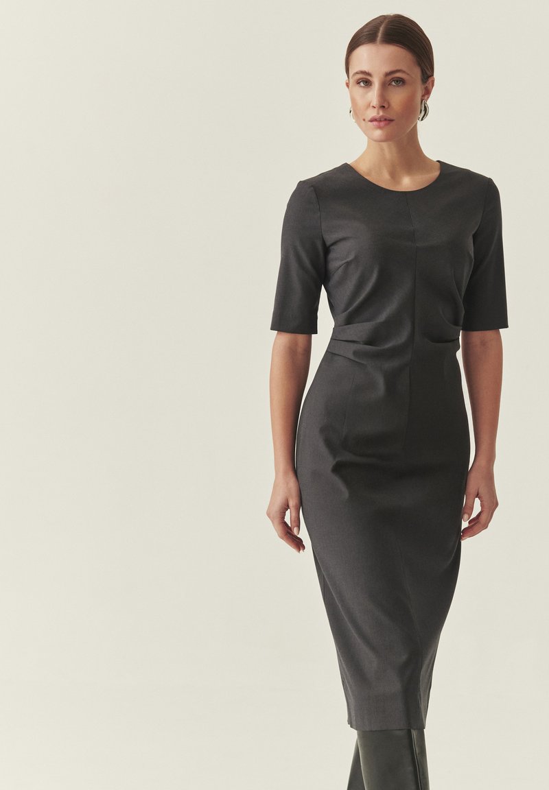 Robe ajustée sombre avec manches courtes, corsage structuré et jupe longueur genou. Confectionnée dans un tissu lisse avec un léger éclat et des lignes épurées.