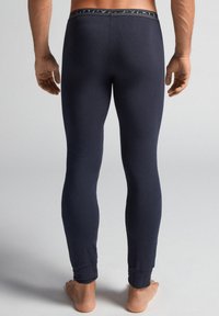 Marine thermal leggings har en tætsiddende pasform, blødt stof og elastisk talje med et diskret mønster; de slutter med tætsiddende manchetter ved anklerne.