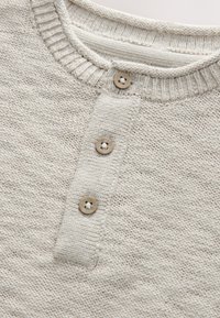 Maglione lavorato a maglia di colore grigio chiaro con scollo tondo, tre bottoni in legno sulla parte anteriore e tessuto strutturato con un motivo sottile.