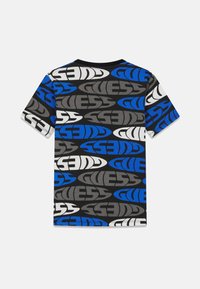 T-shirt à manches courtes avec un fond noir et des logos "GUESS" répétés en bleu, gris et blanc. Matière en coton doux.