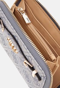 Blaue Geldbörse mit Muster und goldfarbener Reißverschlussbeschläge; Innenteile aus hellbraunem Leder, ausgestattet mit einem Reißverschlussfach und Kartensteckplätzen.