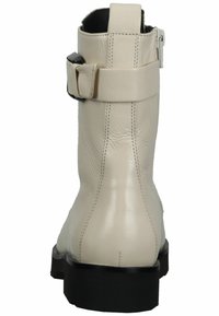 Botines de cuero beige con una superficie lisa, un hebilla lateral y una suela gruesa negra. Las costuras reforzadas aumentan la durabilidad.