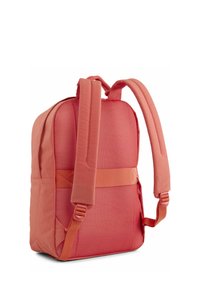 Zaino rosso in tessuto con schienale in mesh imbottito, spallacci regolabili e base piatta. Presenta una finitura testurizzata e un accento sulla cucitura laterale.
