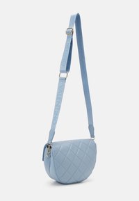 Quiltad ljusblå axelremsväska med böjd form, med ett märkesband och guldfärgade detaljer. Slät struktur och modern design.
