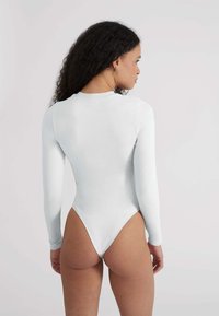 Body a maniche lunghe in tessuto grigio chiaro, caratterizzato da un collo alto, design aderente e una linea di gamba alta. Cuciture minime, texture liscia.