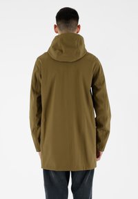 Cappotto impermeabile verde oliva con cappuccio, caratterizzato da un design semplice, un taglio dritto e dettagli di cucitura visibili sulla parte posteriore.